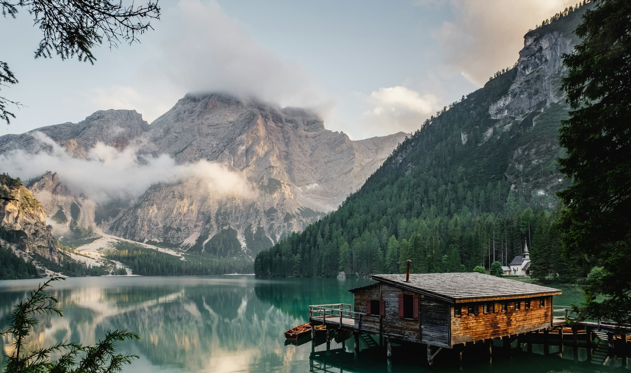 Timber pavilion at the edge of a still lake, reflected at dusk